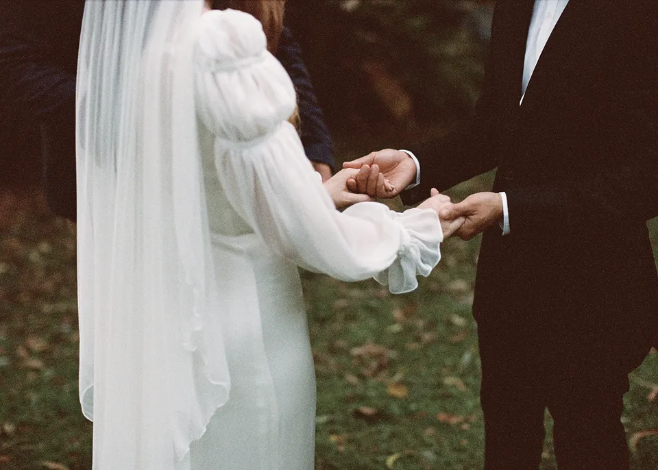 On 35mm film: Detail of the couple's hands during their garden ceremony. At Fig Tree Villa in Ewingsdale, Byron Bay, for an Elopement Collective elopement. Photograph by Bulb Creative.