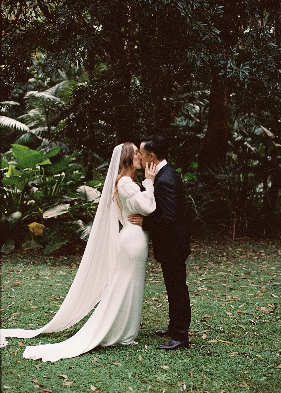 On 35mm film: Elyse and Jonathan kissing on the lawn after their vows. At Fig Tree Villa in Ewingsdale, Byron Bay, for an Elopement Collective elopement. Photograph by Bulb Creative.