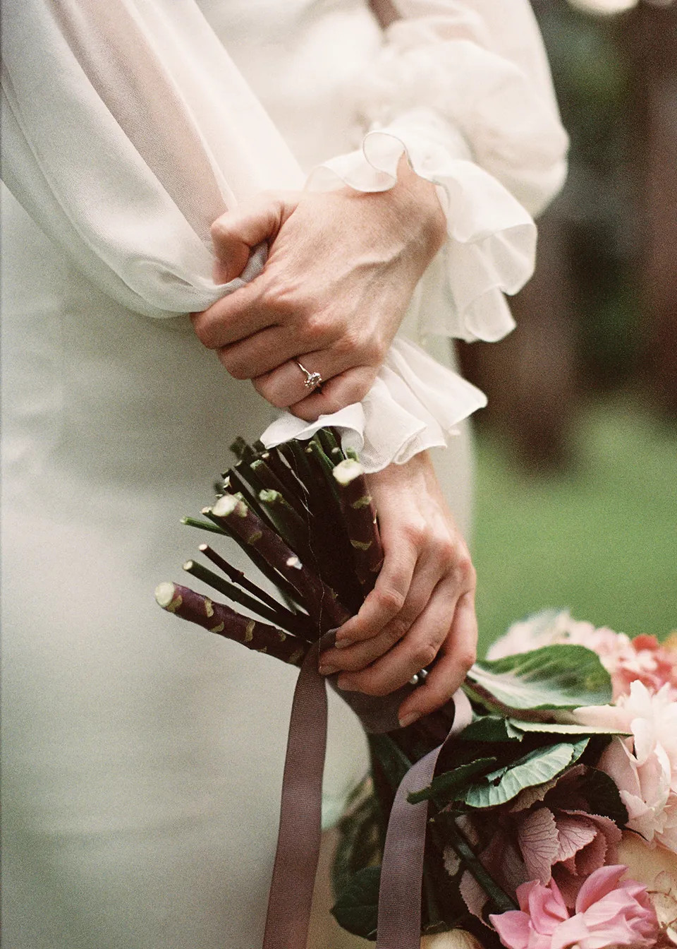 On 35mm film: Close-up of Elyse's wedding ring and gathered sleeve beside her bouquet, with flowers by The Perfect Party Co. At Fig Tree Villa in Ewingsdale, Byron Bay, for an Elopement Collective elopement. Photograph by Bulb Creative.
