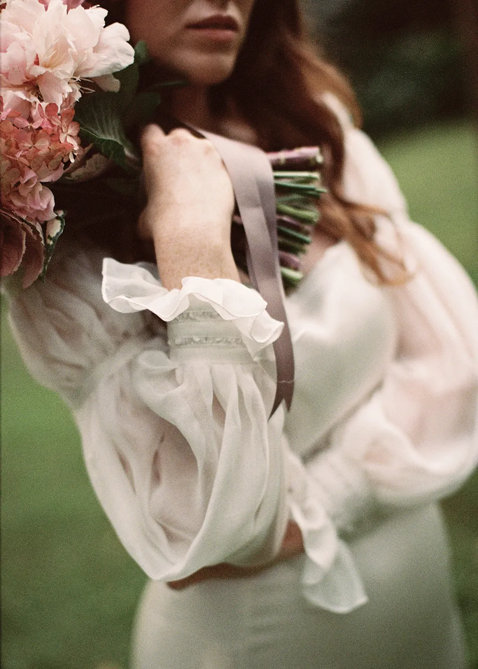On 35mm film: Detail of Elyse's hand, sheer sleeve and bouquet held at her shoulder, with flowers by The Perfect Party Co. At Fig Tree Villa in Ewingsdale, Byron Bay, for an Elopement Collective elopement. Photograph by Bulb Creative.