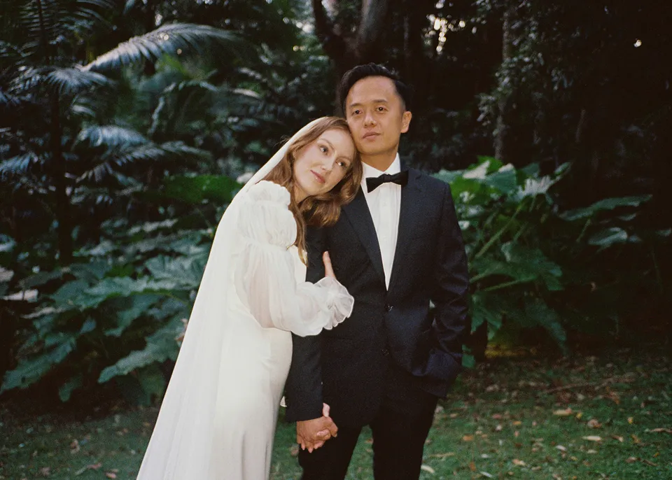 On 35mm film: Elyse leaning against Jonathan's shoulder beneath the tree ferns. At Fig Tree Villa in Ewingsdale, Byron Bay, for an Elopement Collective elopement. Photograph by Bulb Creative.