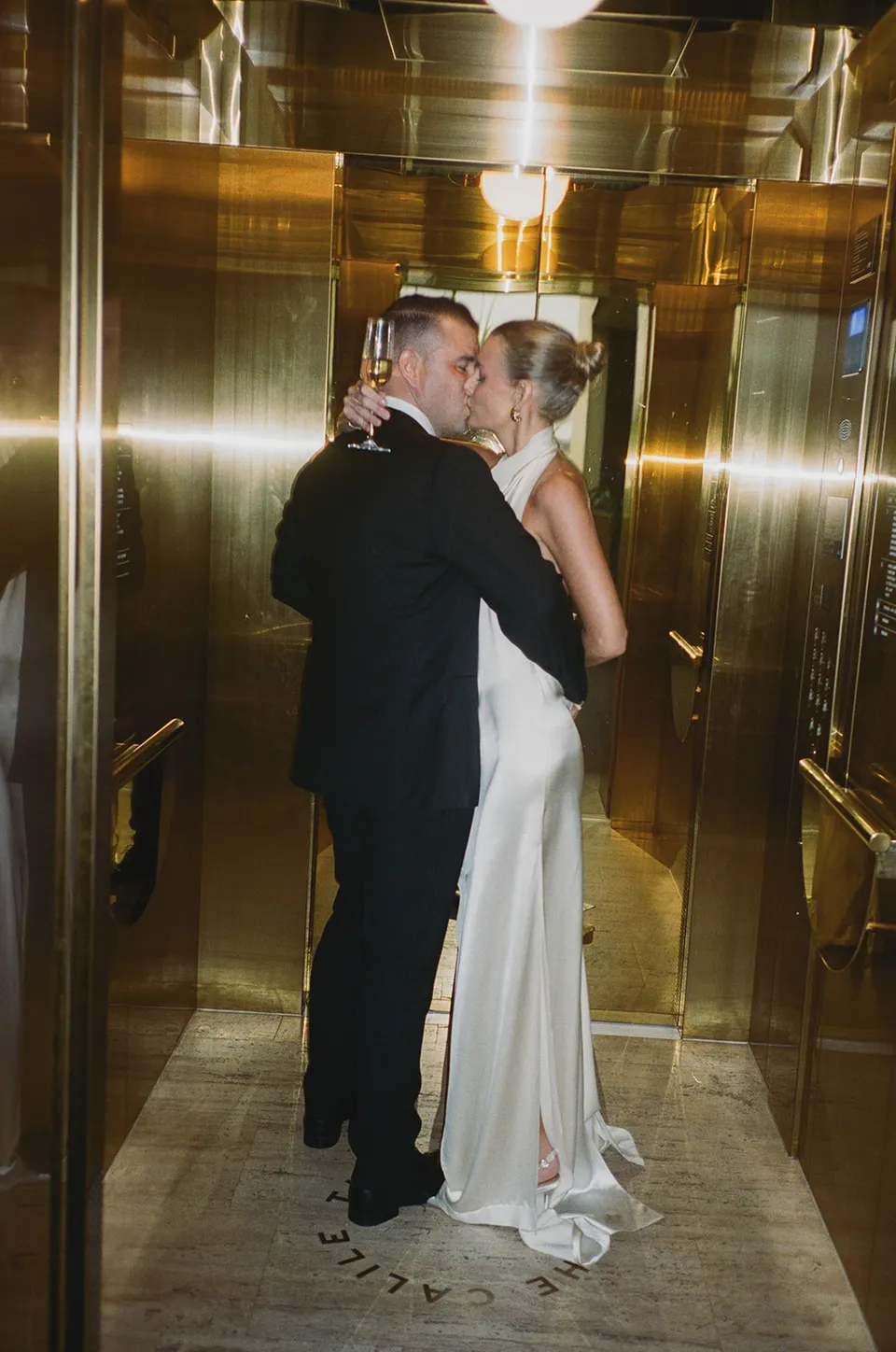 Clare and Matt kissing in a gold mirrored lift, at The Calile Hotel in Fortitude Valley, Brisbane, for an Elopement Collective elopement. Photo by Harley from Bulb Creative.