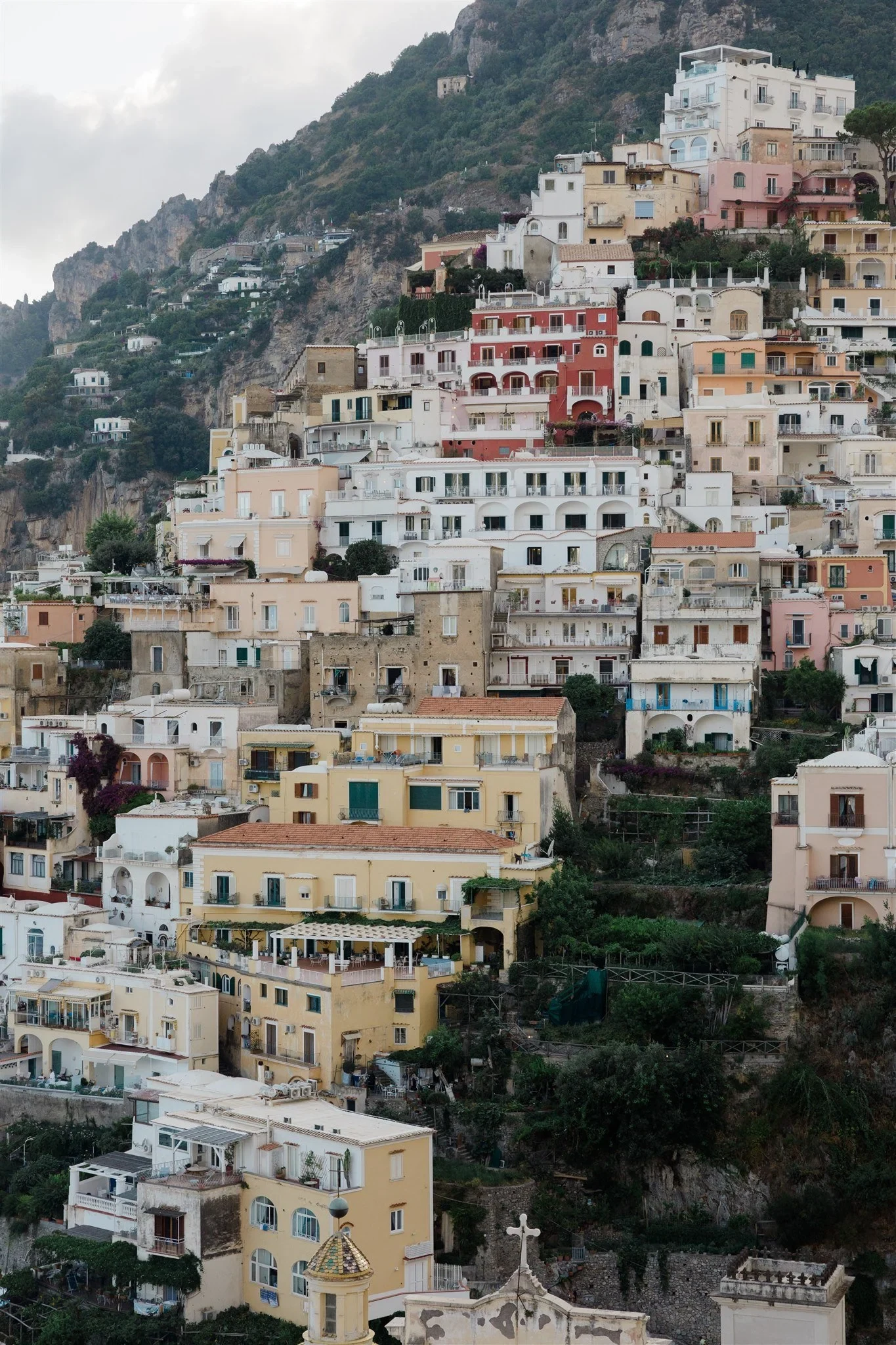 Pastel-coloured houses stacked across the steep hillside above the coastline, in Positano on Italy’s Amalfi Coast, for an Elopement Collective elopement. Photo by James from House of Love.