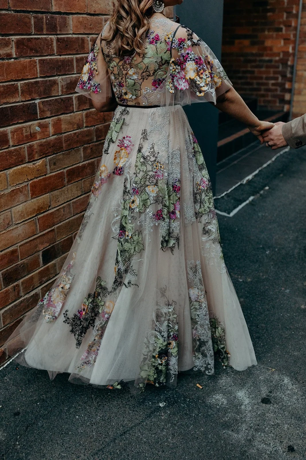 Detail of Victoria’s flowing floral skirt as she walks through a brick-lined laneway holding Daniel’s hand, in Fortitude Valley, Brisbane, for an Elopement Collective elopement. Photo by Tessa Shannon.