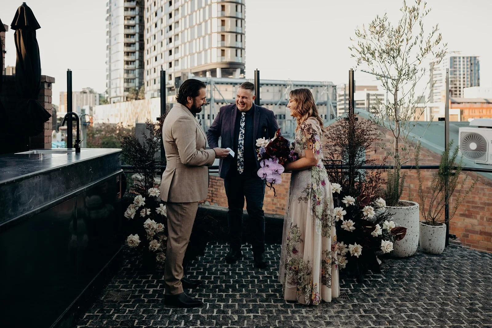 Daniel reading his vows to Victoria with celebrant Josh Withers beside them, at Agnes Restaurant in Fortitude Valley, Brisbane, for an Elopement Collective elopement. Photo by Tessa Shannon.