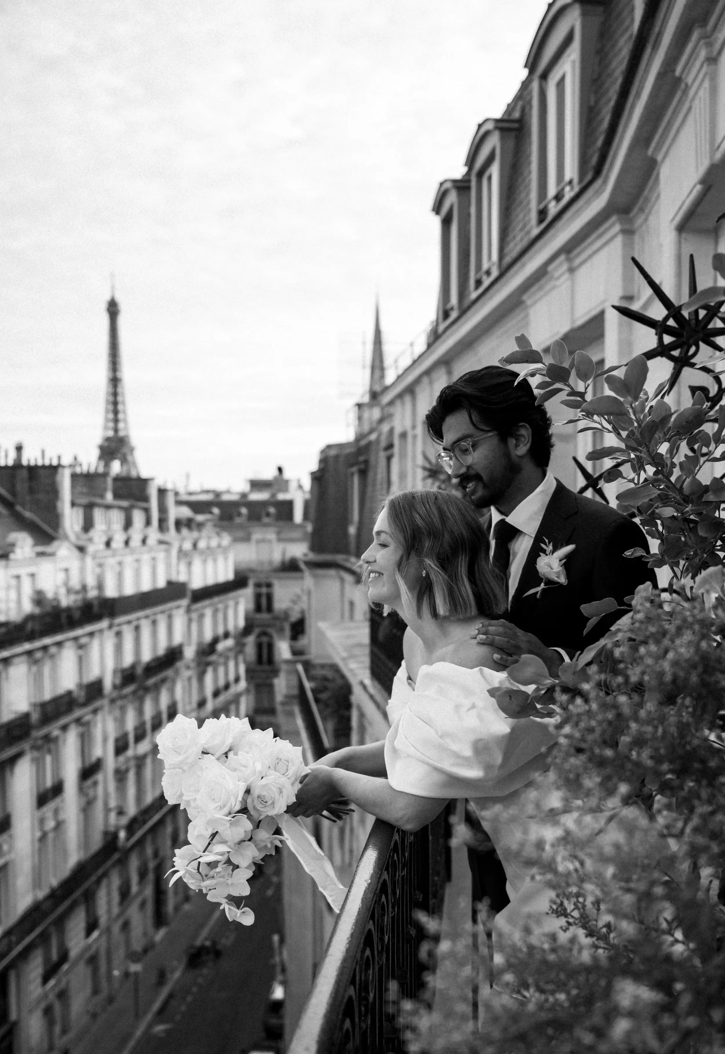 A couple together on a Paris balcony overlooking the Eiffel Tower, during an elopement created by The Elopement Collective.