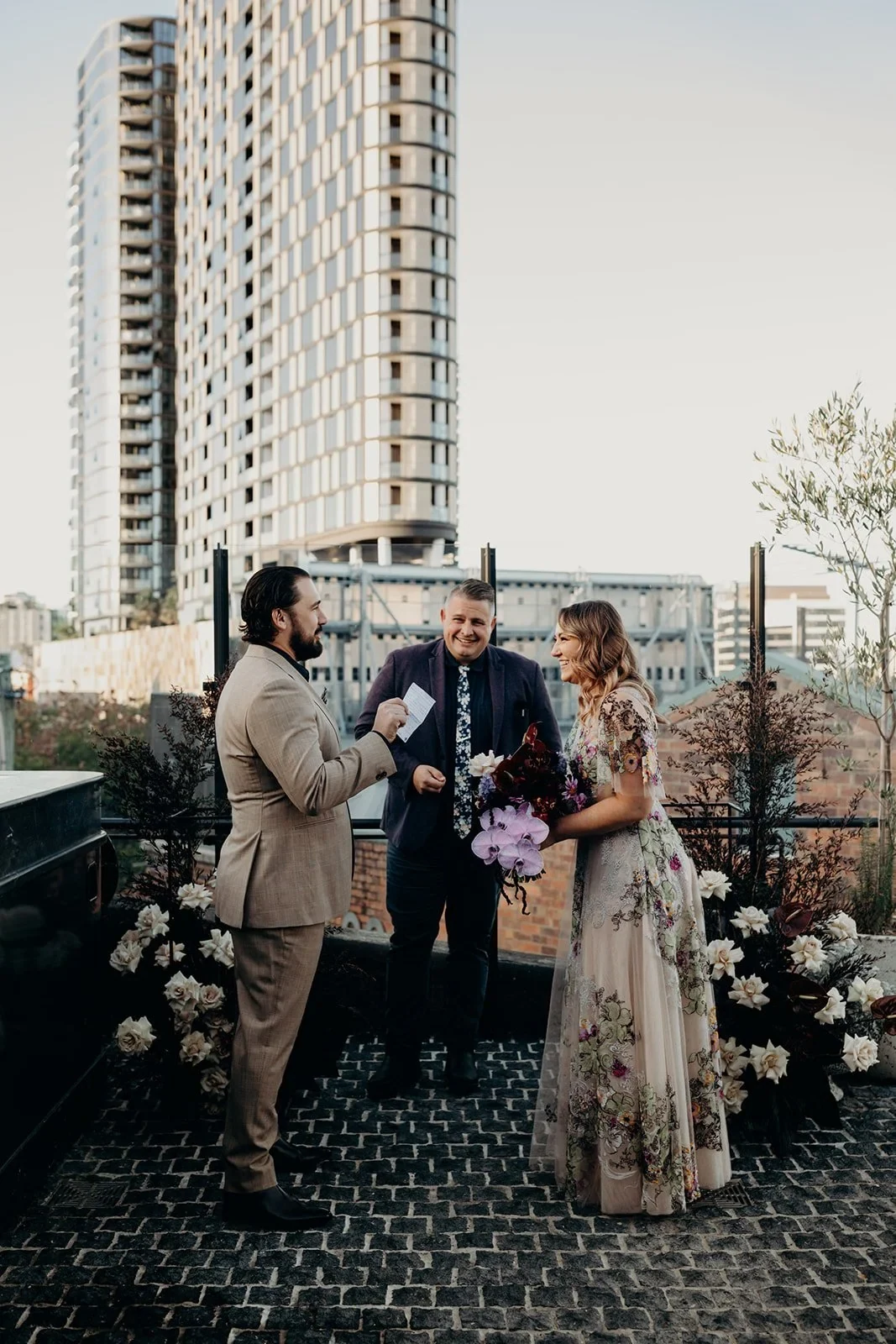 Daniel speaking during the ceremony with Victoria and celebrant Josh Withers on the rooftop terrace, at Agnes Restaurant in Fortitude Valley, Brisbane, for an Elopement Collective elopement. Photo by Tessa Shannon.