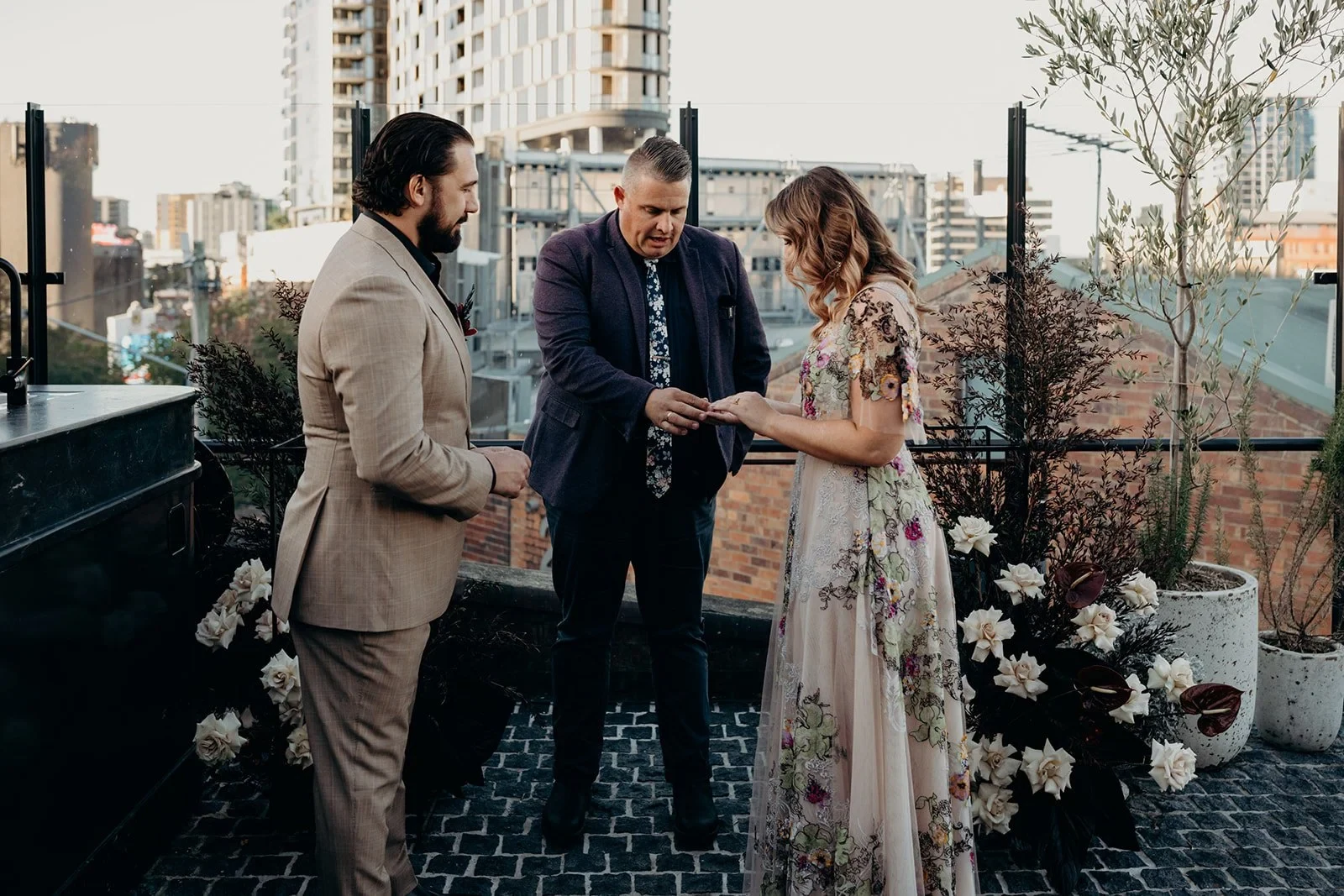 Celebrant Josh Withers looking down at Victoria and Daniel’s hands during the ring exchange, at Agnes Restaurant in Fortitude Valley, Brisbane, for an Elopement Collective elopement. Photo by Tessa Shannon.