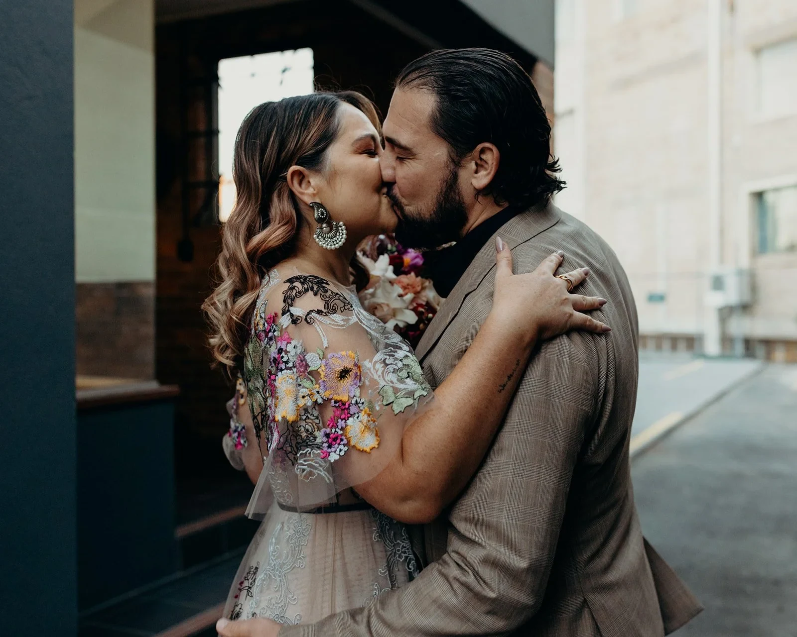 Close-up of Victoria and Daniel kissing with her arms around his shoulders, in Fortitude Valley, Brisbane, for an Elopement Collective elopement. Photo by Tessa Shannon.