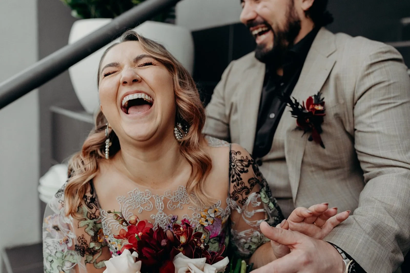 Victoria laughing beside Daniel while seated on outdoor steps, in Fortitude Valley, Brisbane, for an Elopement Collective elopement. Photo by Tessa Shannon.